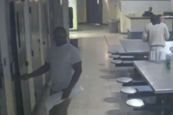 A surveillance image of James Albert walking into his cell with an unidentified package.